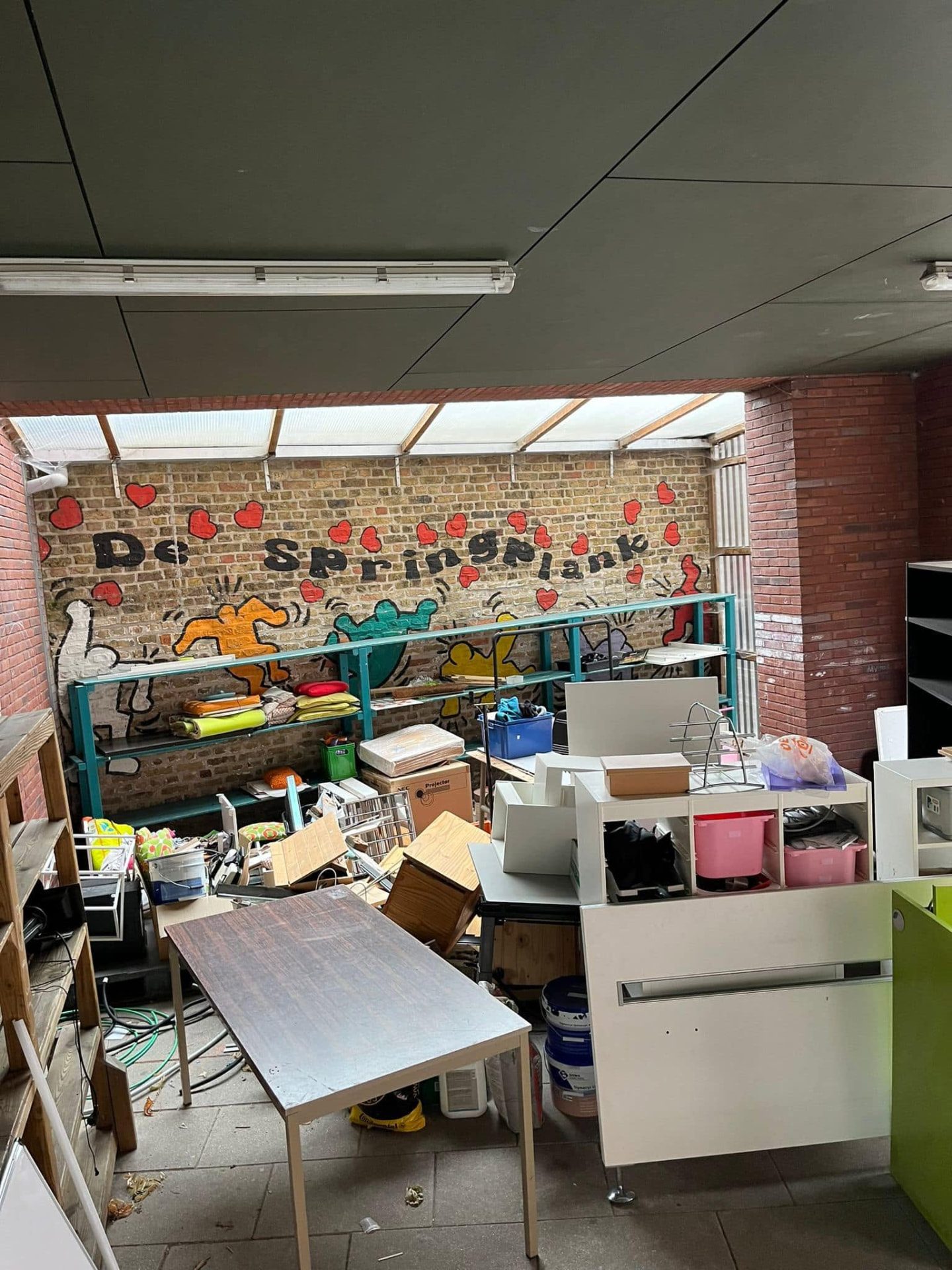 Overdekte ruimte van een school vol meubilair en materiaal vóór de volledige ontruiming