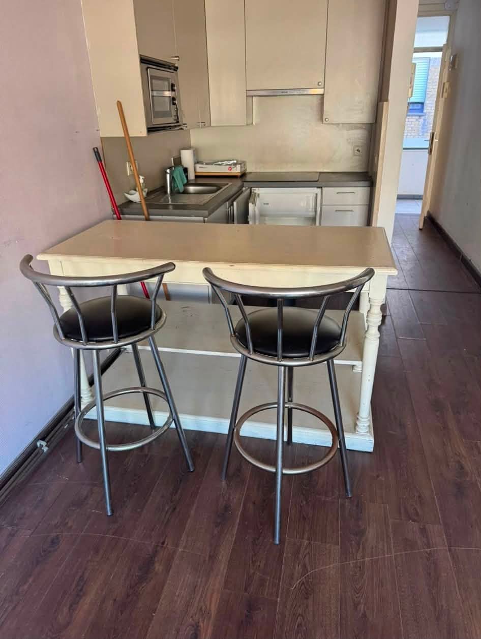 Studio voor opruiming in Knokke: keukenhoek met tafel en barkrukken vóór de start van de werken