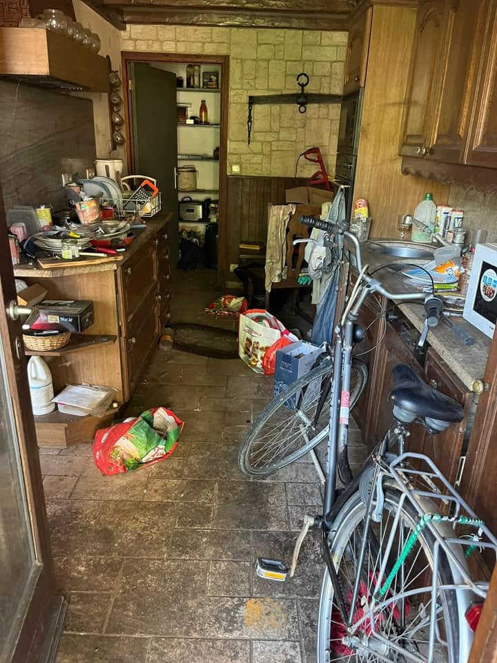 Keuken en doorgang vol spullen en fietsen in een volledig te ontruimen woning