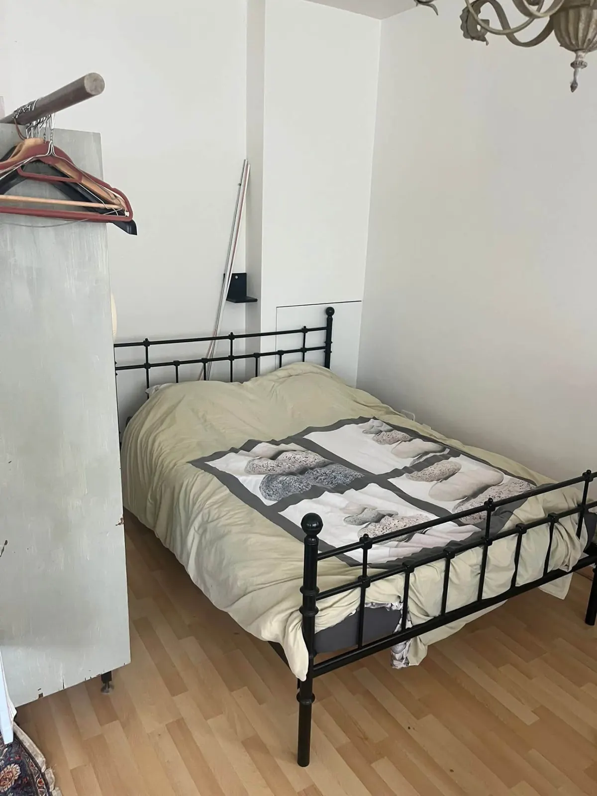 Slaapkamer met bed en losse kastdeuren vóór de woningontruiming in Brugge